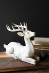 White deer figurine on a wooden surface with a dark background
