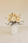 White vase with beige flowers on a light wooden floor and beige wall background
