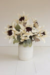 White vase with artificial sunflowers on a white floor