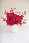 Red floral arrangement in a white vase on a light background