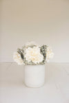 White vase with white flowers on a light beige background