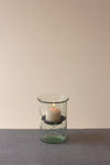 Candle in a glass holder on a gray surface with a beige background