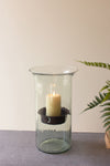 Clear glass lantern with a candle inside on a neutral background