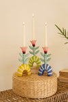 Colorful candle holder with three candles on a woven surface