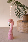 Pink flamingo candle holder with a candle on a neutral background