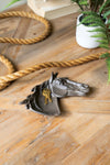 Decorative horse head with a key on a wooden surface with gold rope and a plant.