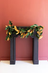Decorative leaf garland on a fireplace against a pink wall