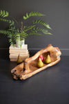 Wooden tray with pears and a plant on a dark surface