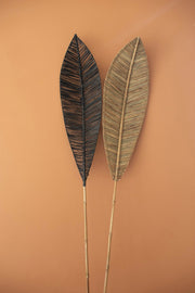 Two decorative leaves on sticks against a brown background