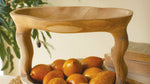 Wooden bowl with oranges on a woven surface