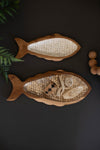 Two wooden fish-shaped decorative plates with intricate carvings on a dark background.