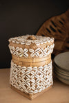 Decorative woven container with shell patterns on a wooden surface
