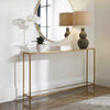 Console table with decorative items including a lamp and plants against a white wall.