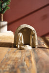Small nativity scene figurine on a wooden surface with a blurred background