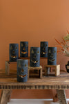 Set of blue ceramic jack-o'-lantern candle holders on a wooden table against an orange wall.