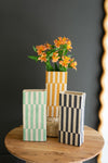 Three decorative vases with different patterns on a wooden table against a dark background
