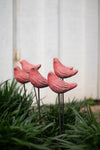 Pink bird-shaped garden stakes in grass with a blurred background