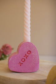 Pink heart-shaped candle with 'XOXO' on a wooden surface