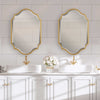 Bathroom vanity with two gold-framed mirrors, white sinks, and decorative flowers.