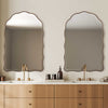 Bathroom vanity with two mirrors, sinks, and wooden cabinets.