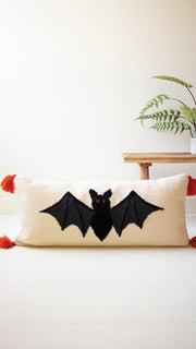 Decorative pillow with bat design on a plain background