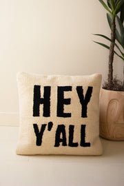 Beige pillow with 'HEY Y'ALL' text on a light background