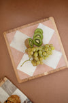 Fruit platter with kiwis and grapes on a decorative cutting board.