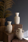 Set of white ceramic vases on wooden blocks against a dark background