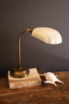 Vintage-style desk lamp with marble base on a wooden surface against a dark background