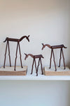 Set of four bronze deer sculptures on wooden stands against a white wall.