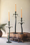 Decorative candle holders with candles on a wooden surface against a neutral wall.