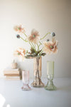 Floral arrangement in a vase with two glass vases on a white surface.