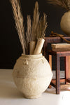 Decorative stone vase with dried plants on a white surface