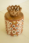 Decorative stool with floral pattern and wooden top on a light background