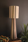 Striped lamp with a wooden base against a dark wall