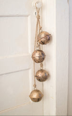 Decorative brass bells hanging on a white wall