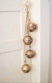 Decorative brass bells hanging on a white wall