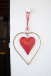 Heart-shaped red ornament hanging on a white door