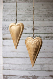 Two gold heart-shaped hanging decorations on a wooden background