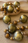 Necklace with large green and gold beads on a textured surface