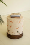 Small round stool with floral pattern and woven base on a light background