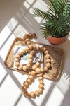 Wooden beads on a woven tray with a plant in the background