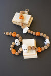 Decorative Halloween garland with beads shaped like ghosts and pumpkins on a dark background