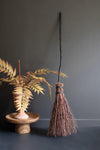 Decorative broom and plant against a dark gray wall