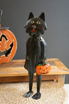 Black cat figurine with a pumpkin, Halloween-themed decor.