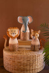 Wooden animal figurines including a lion, elephant, and cheetah on a woven basket with a brown background.
