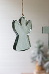Glass angel ornament hanging against a neutral background