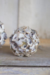 Decorative ball made of seashells on a wooden surface with a neutral background