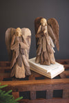Two wooden angel figurines on a dark surface with a plain background
