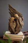 Wooden angel sculpture on top of books with a gray background